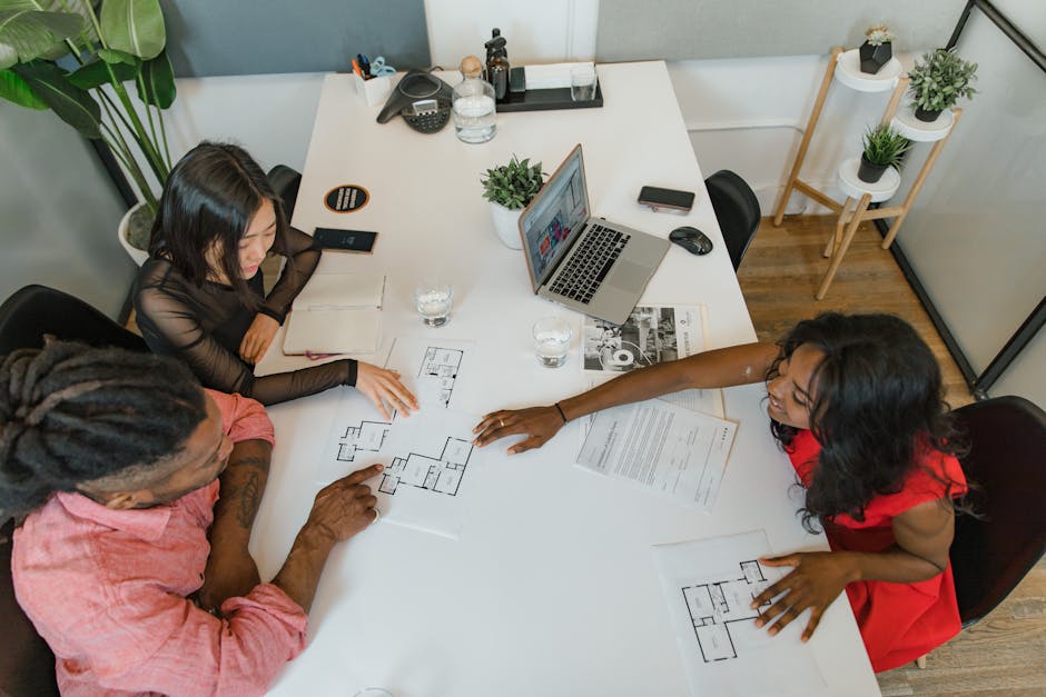 Business team in a modern office reviewing architectural floor plans during a casual meeting.