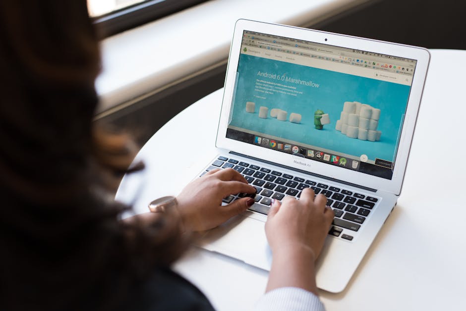 Businesswoman working on laptop with Android 6.0 Marshmallow webpage open.
