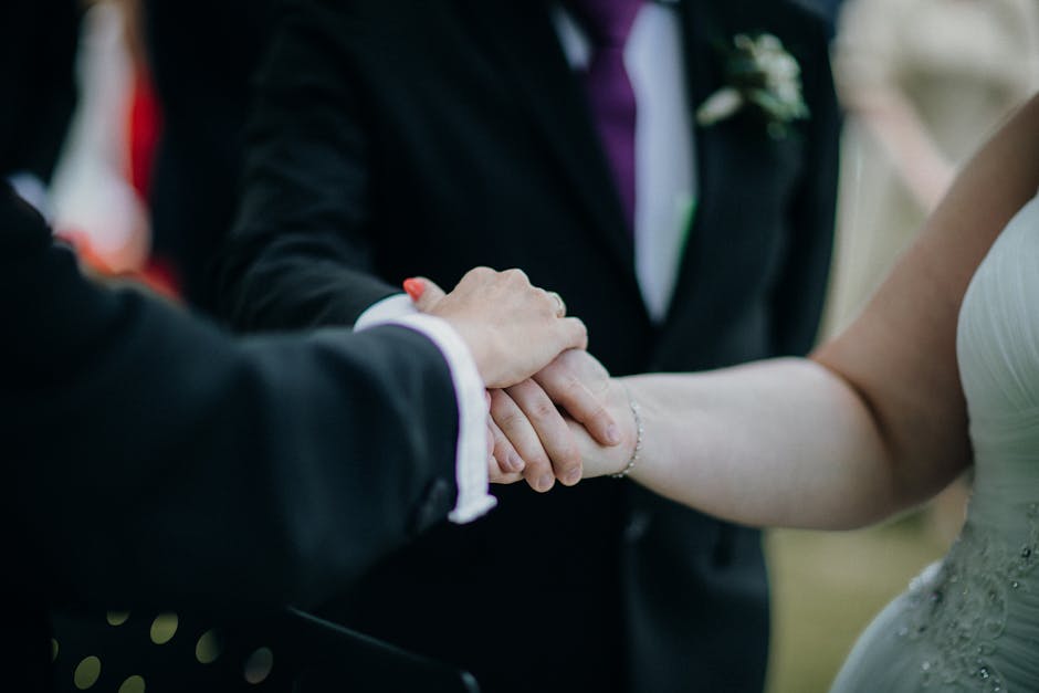 Close-up of a couple holding hands during a wedding ceremony, symbolizing love and commitment.