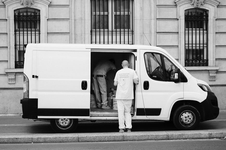 Monochrome image of a delivery van with workers, showcasing urban logistics.