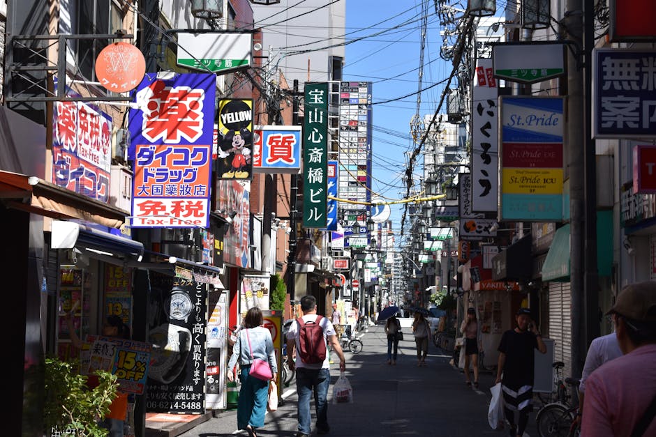Bustling urban street in Osaka with colorful advertisements and pedestrians in daylight.