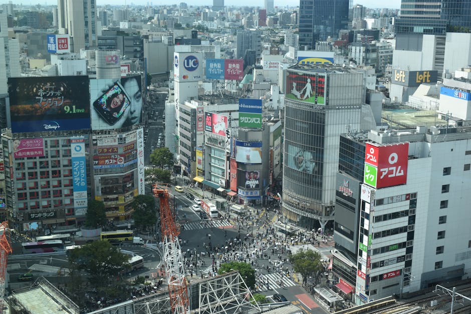 Vibrant aerial view of bustling Shibuya Crossing in Tokyo filled with pedestrians and colorful billboards.