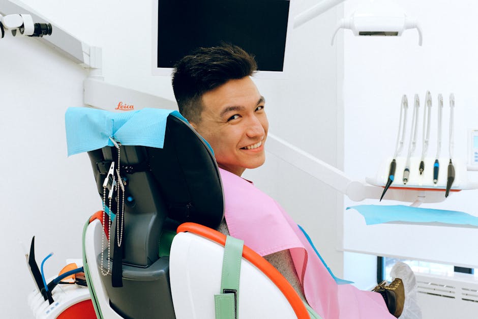 Young man smiling in a dental chair at a modern clinic with equipment in view.