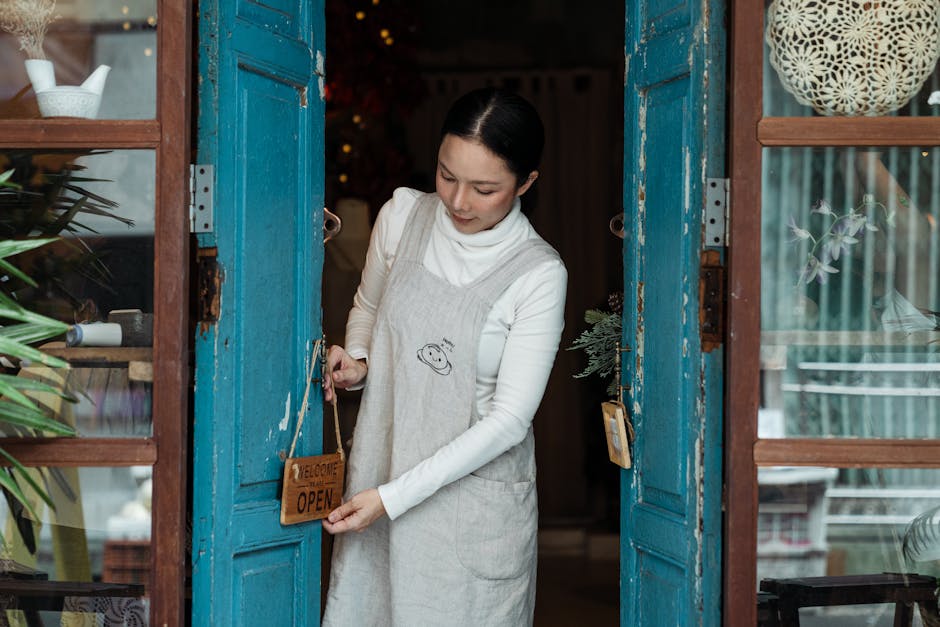 Positive Asian female in casual clothes hanging open sign on shabby blue door of rural weathered shop