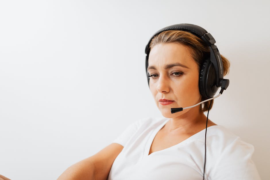 Focused woman wearing a headset working in customer support with a white background.
