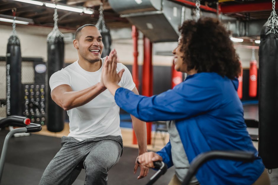 Cheerful plump black female trainee and smiling fit male instructor clapping each others hands in modern gym