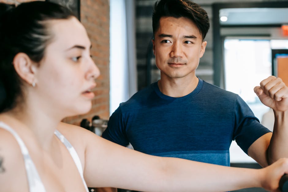 Fit young trainer giving instructions to plus size female athlete doing exercise on sports equipment in gym