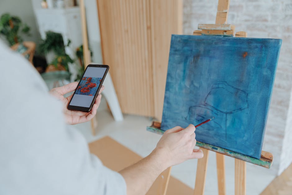 Artist uses smartphone to guide painting process on canvas indoors.