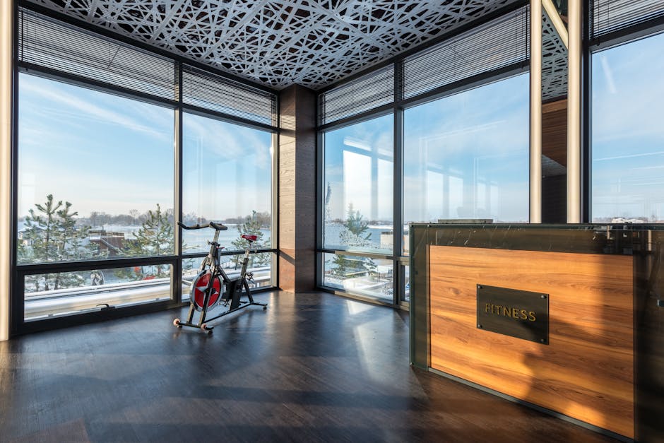 Modern exercise bike placed in spacious fitness center with wooden floor and panoramic windows overlooking sea on sunny day