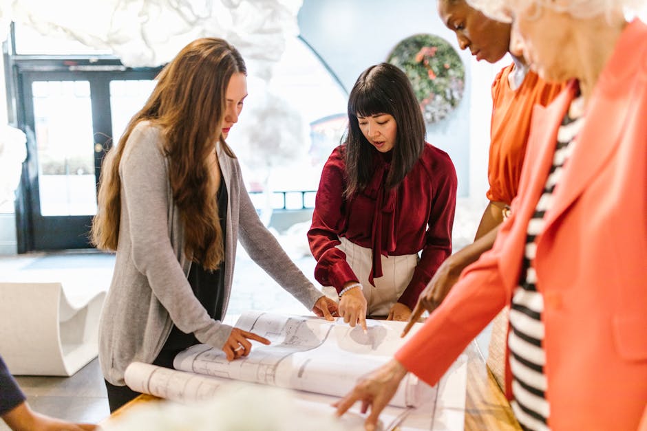 A diverse group of women in an office discussing plans and ideas around a table.