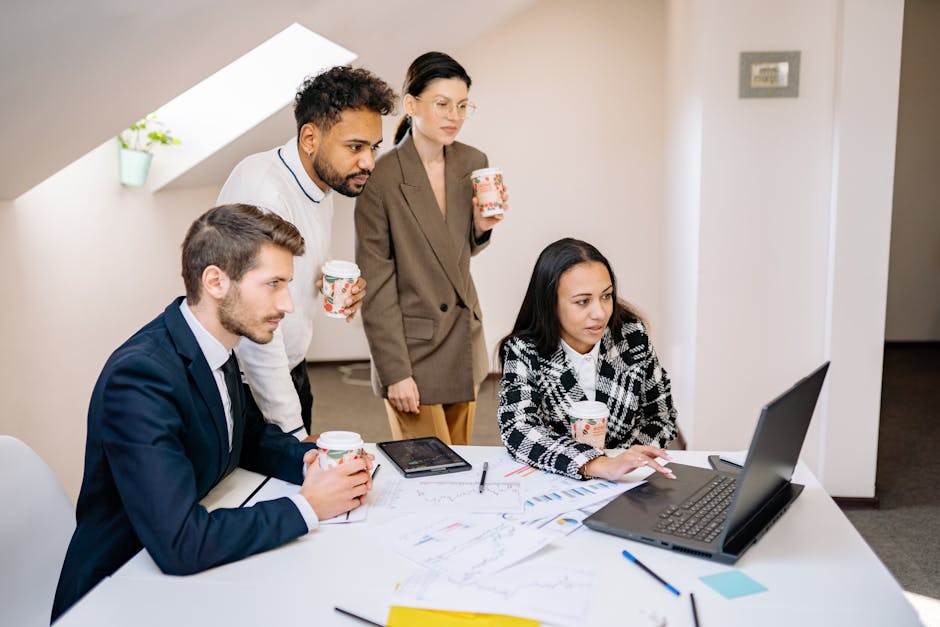 A diverse team collaborates in a modern office, using laptops and tablets for planning and brainstorming.
