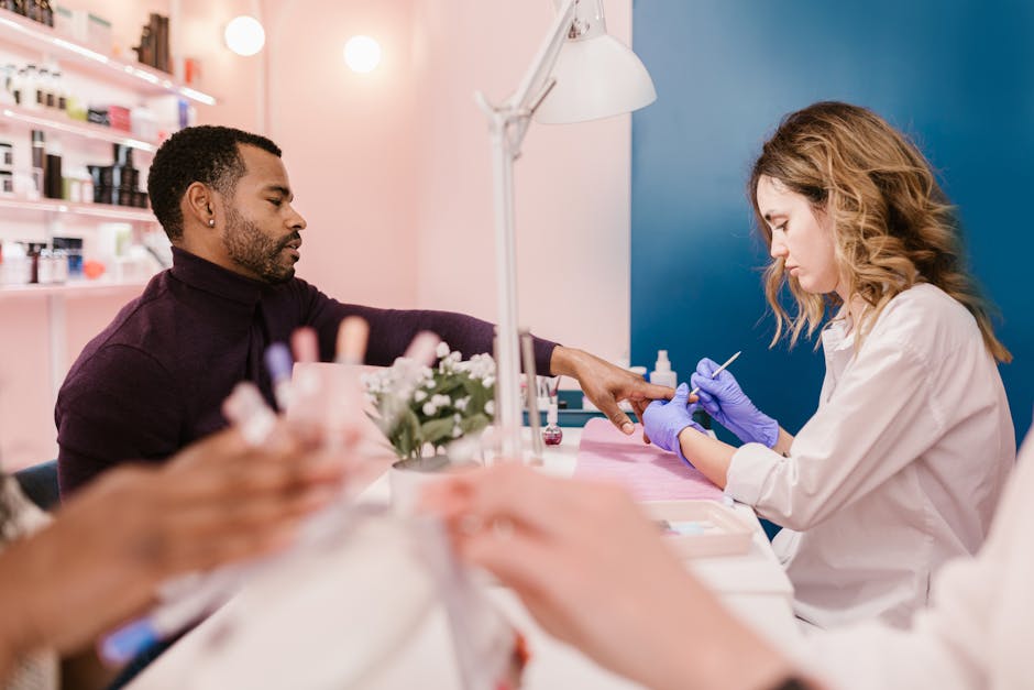A man receives a manicure from a nail technician in a stylish, modern salon setting.