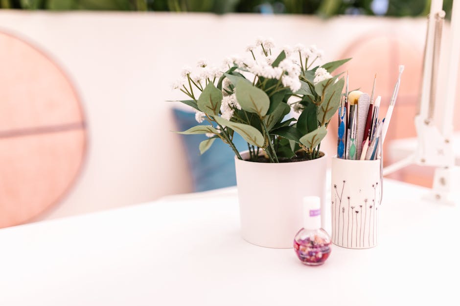 Modern nail salon setting featuring a white planter with green leaves and a nail polish bottle on a countertop.