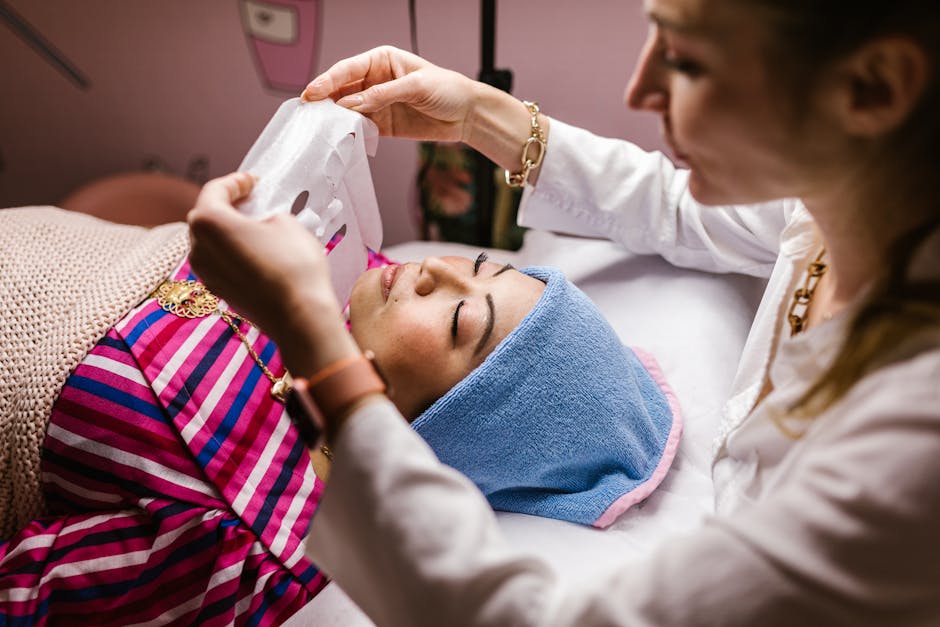 A beautician applies a sheet mask during a facial treatment for relaxation and skincare rejuvenation.