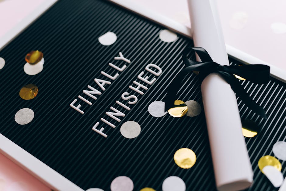Close-up of a graduation diploma and letter board with "Finally Finished," surrounded by confetti.