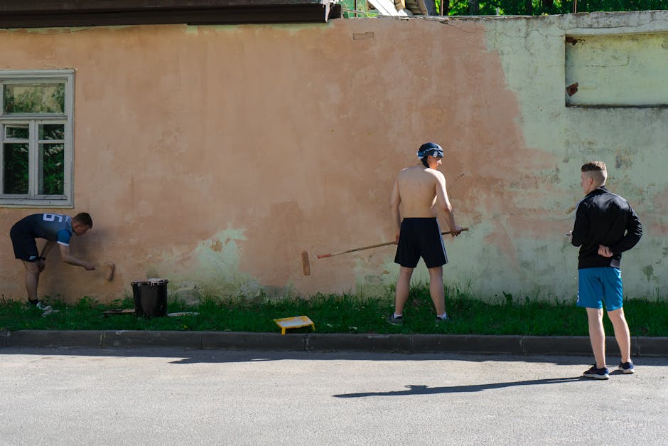 Three men painting a wall on a sunny day, showcasing teamwork and urban lifestyle.