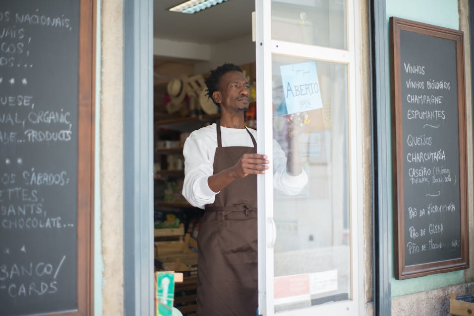 A man in an apron opens a grocery store door in Portugal, ready for business.