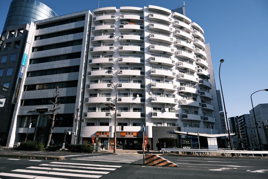 White residential building exterior with adjacent street and crosswalk in Nagoya, Japan.
