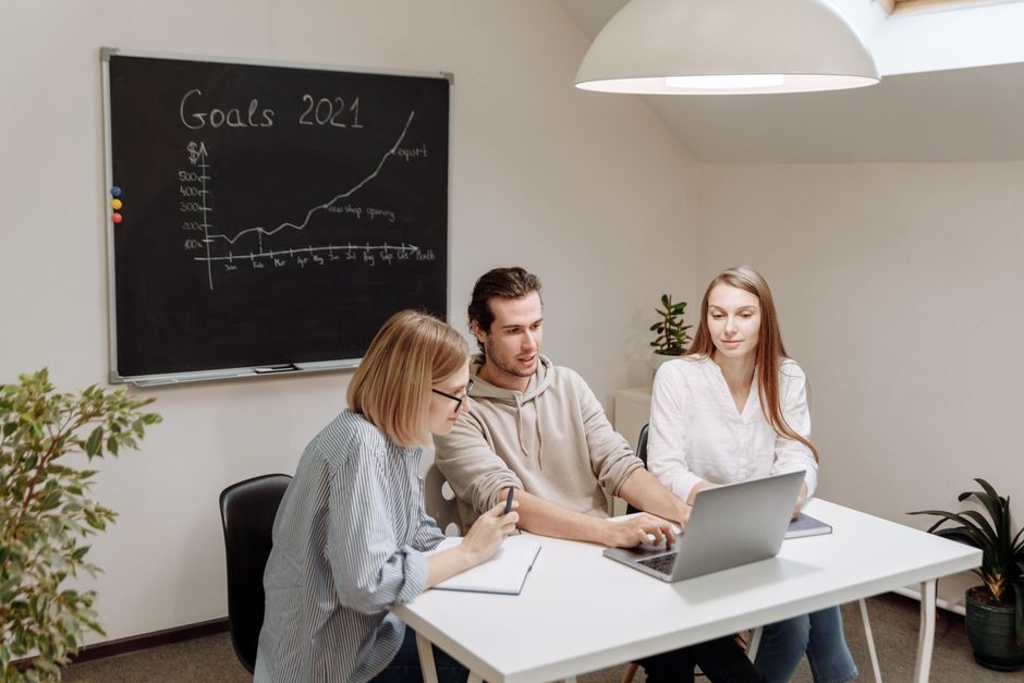 Coworkers collaborate in a modern office setting, planning and discussing 2021 goals.