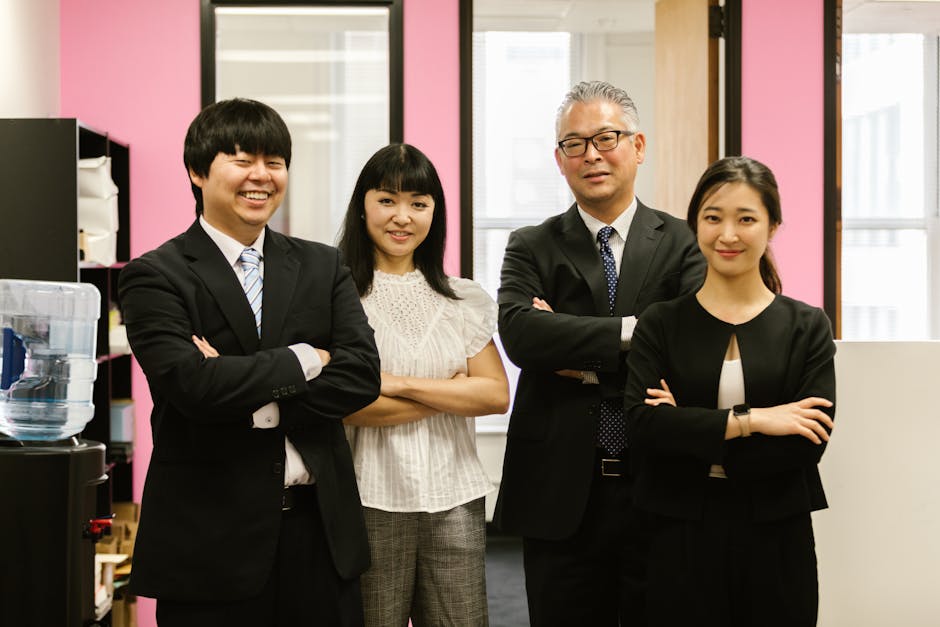 Four business professionals standing with confidence in a modern office setting.