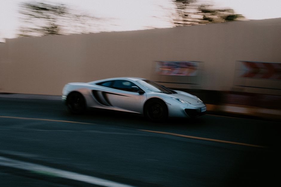 Dynamic shot of a silver sportscar speeding on a city street, capturing motion and speed.