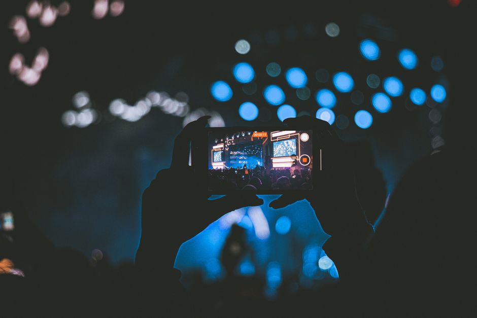A vibrant concert scene captured through a smartphone, showcasing lively bokeh lights.