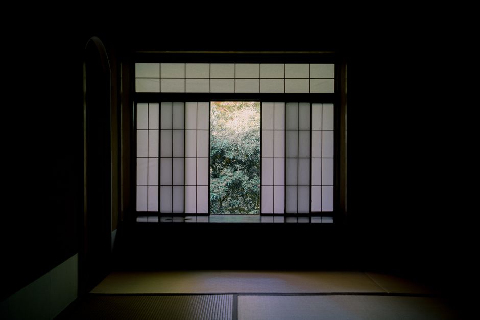 Serene view from a Japanese room through a shoji window to a tranquil garden.