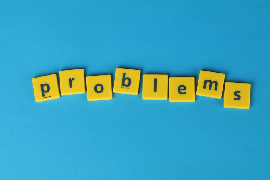 Yellow letter tiles spelling 'problems' arranged on a vibrant blue background, creating a textual concept image.