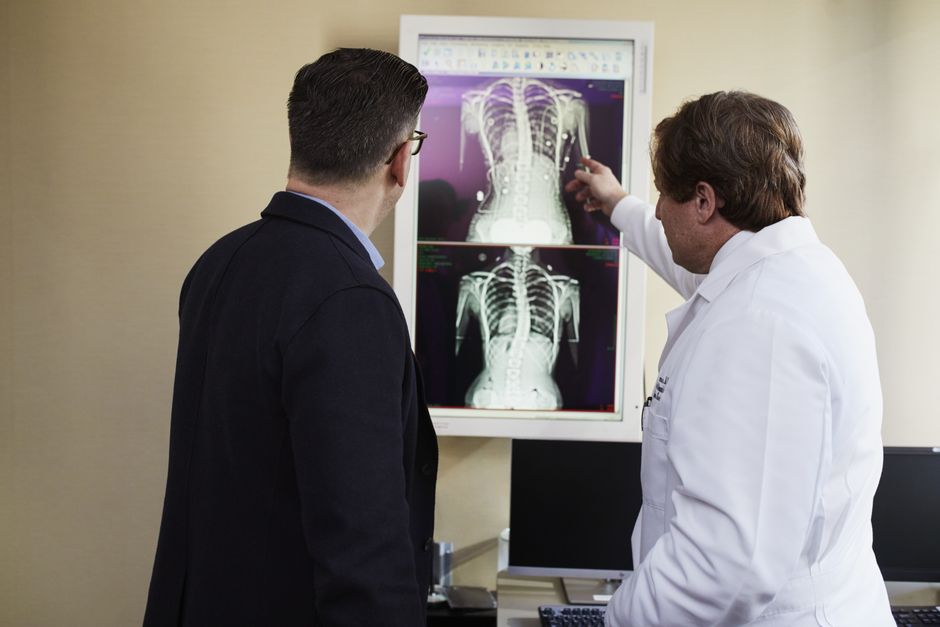 A doctor explains X-ray results to a patient in a clinical setting, highlighting healthcare communication.
