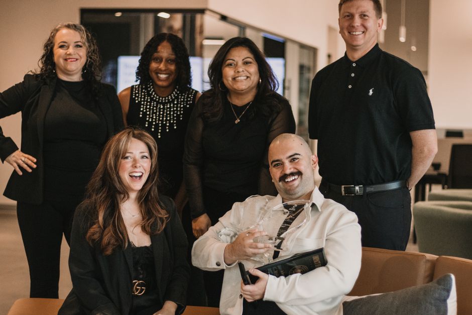 Diverse group of real estate professionals posing confidently in office environment.