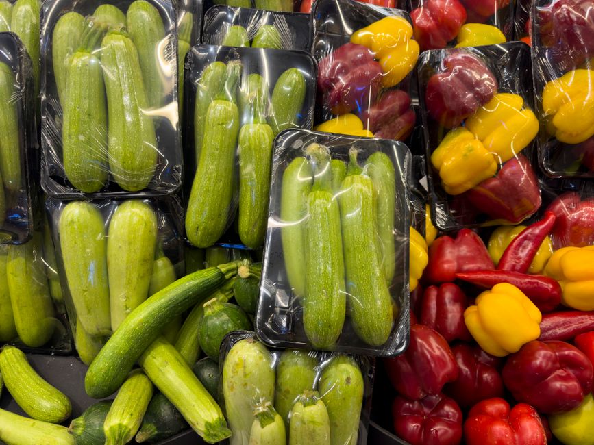 Fresh organic zucchini and bell peppers on display, showcasing vibrant colors and natural produce at a market.