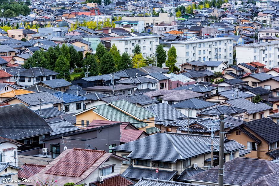 Aerial view of traditional Japanese roofs in an urban neighborhood at daytime.