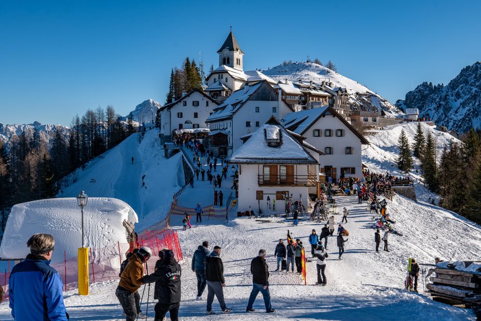 Vibrant winter scene at an Italian ski resort with skiers and snow-covered buildings.
