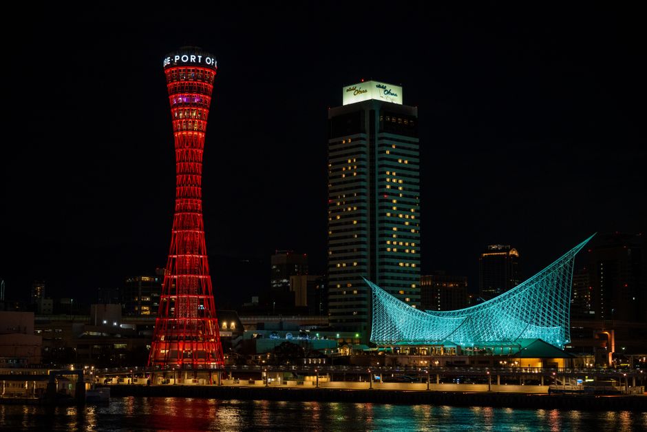 Stunning night view of Kobe Port Tower and Maritime Museum reflecting on water in Kobe, Japan.