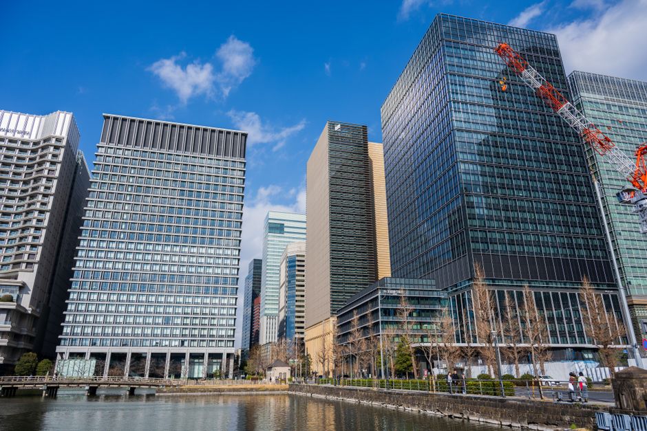 High-rise buildings reflecting on water under blue skies in Tokyo, Japan.