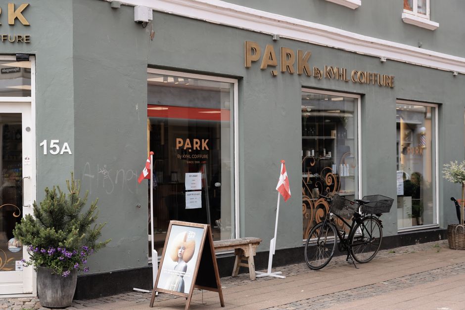 A stylish coiffure shopfront in Copenhagen with a bicycle and Danish flags outside.