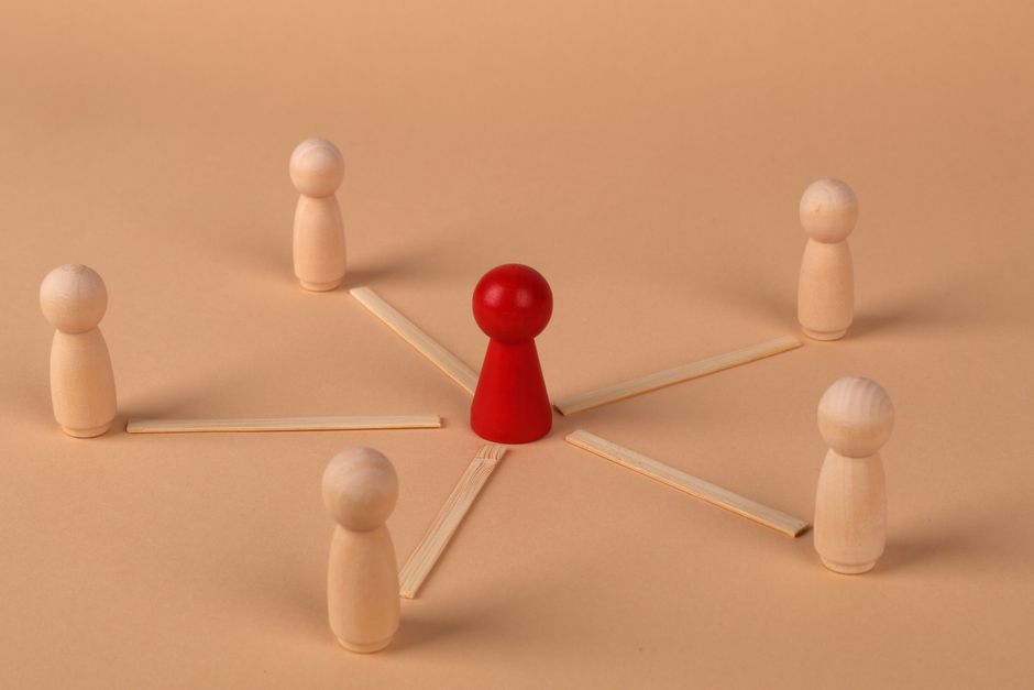 Wooden figures with red leader representing teamwork and influence.