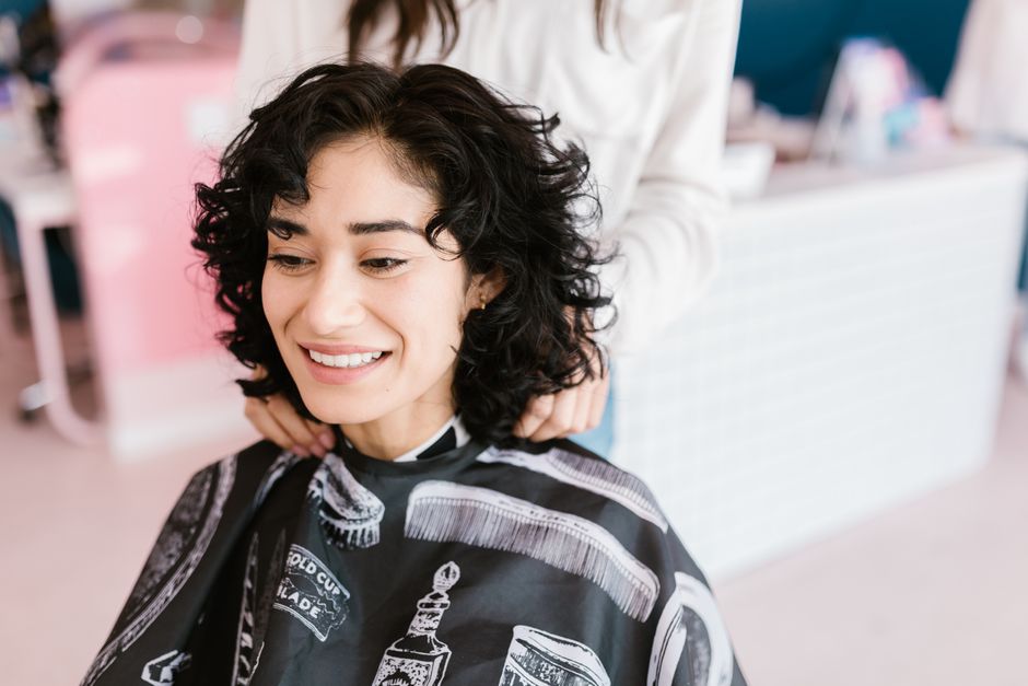 A cheerful woman getting a haircut at a salon, showcasing a positive self-care experience.