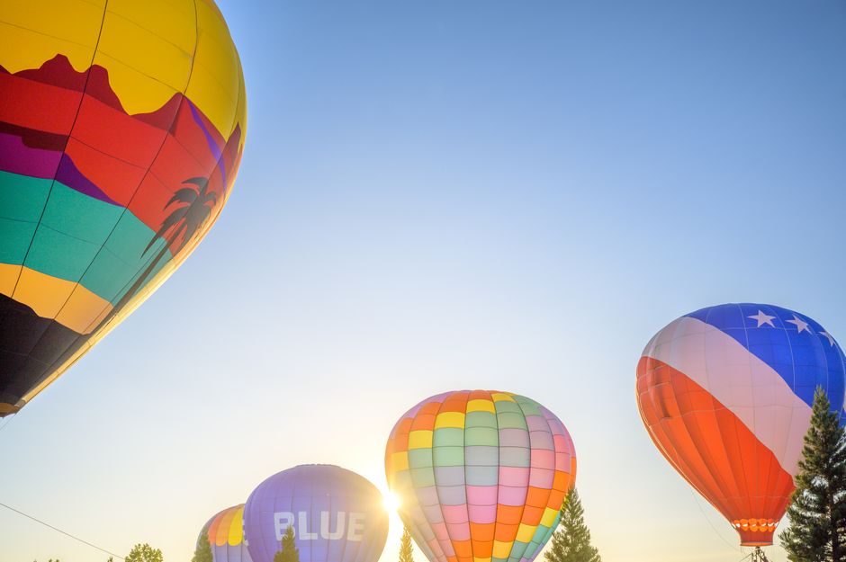 Colorful hot air balloons float under a clear blue sky, capturing a bright and lively atmosphere.